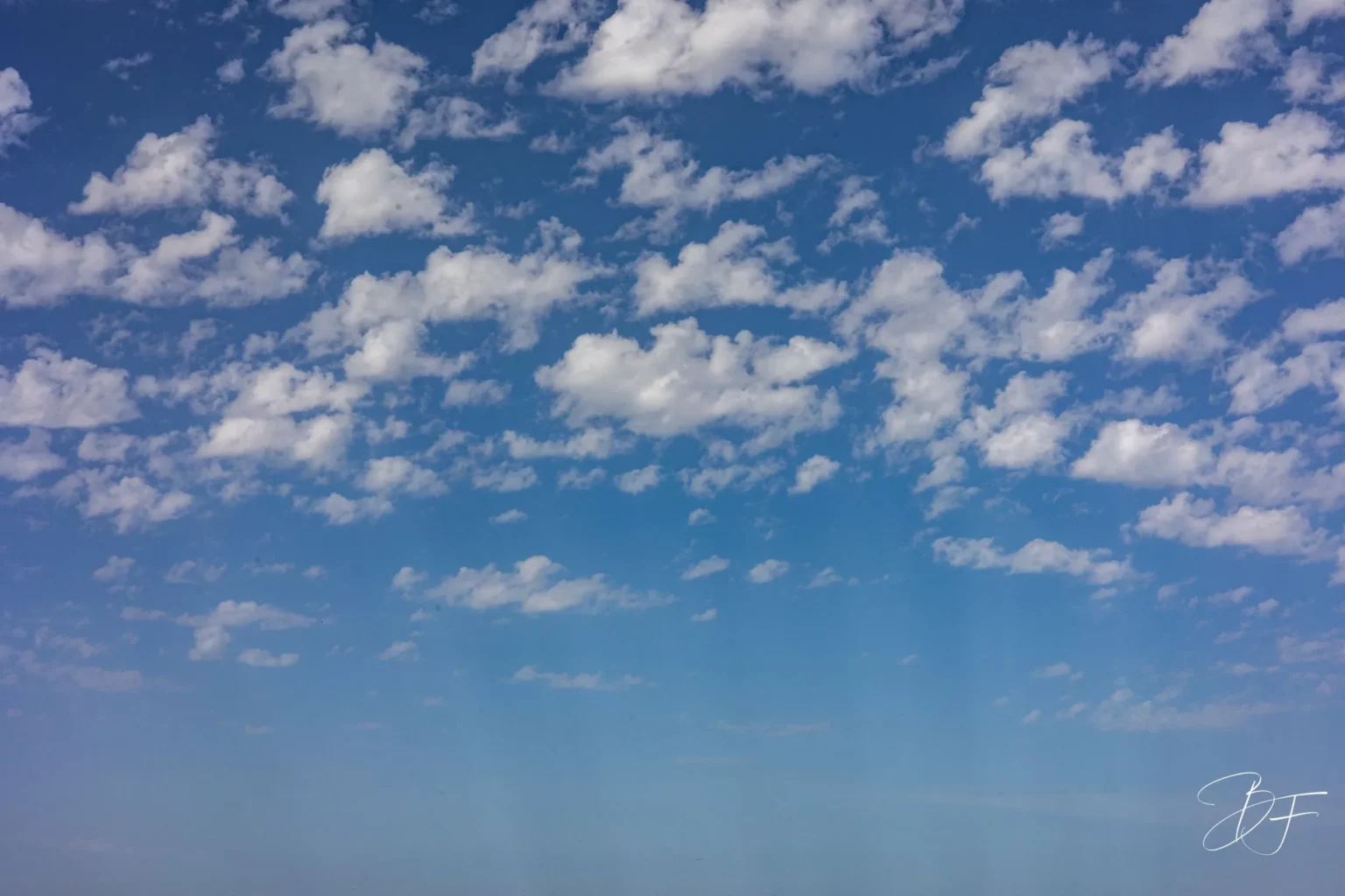 A blue sky dotted with small white clouds