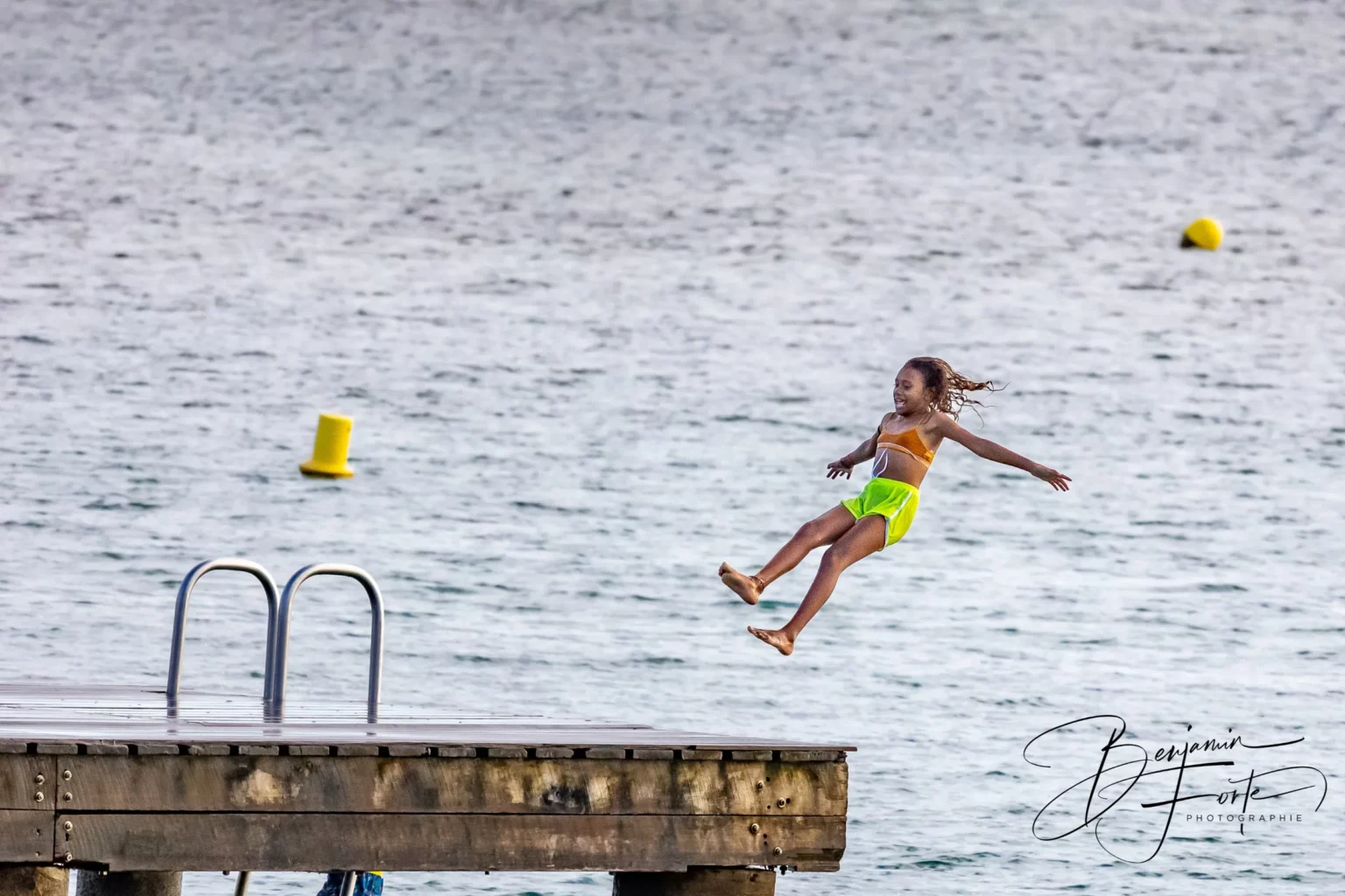 A young girl jumps off a pontoon into the lagoon